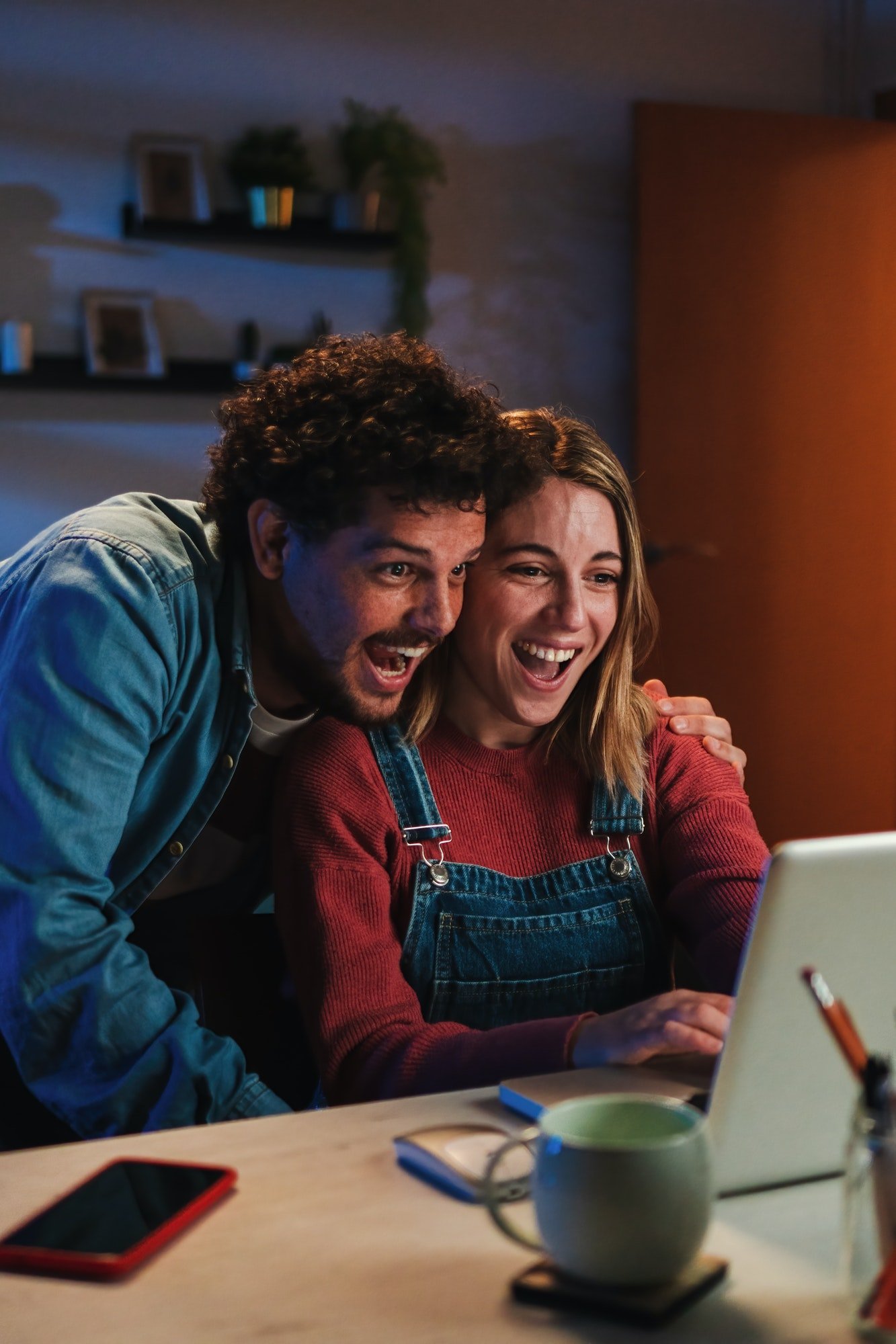 Vertical. Happy young caucasian couple smiling and having fun watching streaming videos on social